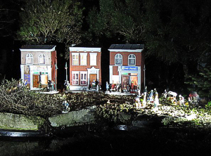 This town scene is lit by internal bulbs hooked up to a Malibu lighting system and by floodlights from three different directions, so you can see it clearly well after dark.  Click for a bigger photo.