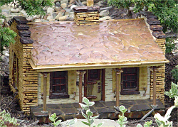 This model represents a the Firman dairy house, a 1920s-era structure, which is still on the property.  The original building has cow head sculptures on the top of each porch post.  Note the leaf roof and the twig trim around the door and windows.  Click for bigger photo.