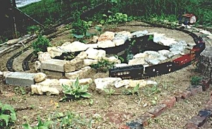 This photo, taken about April, 1999, shows the connecting pool and pond from another angle. The 'back' edge of the connecting pool now backs up against the solid concrete blocks which would form the walls of my first attempt at a tunnel.